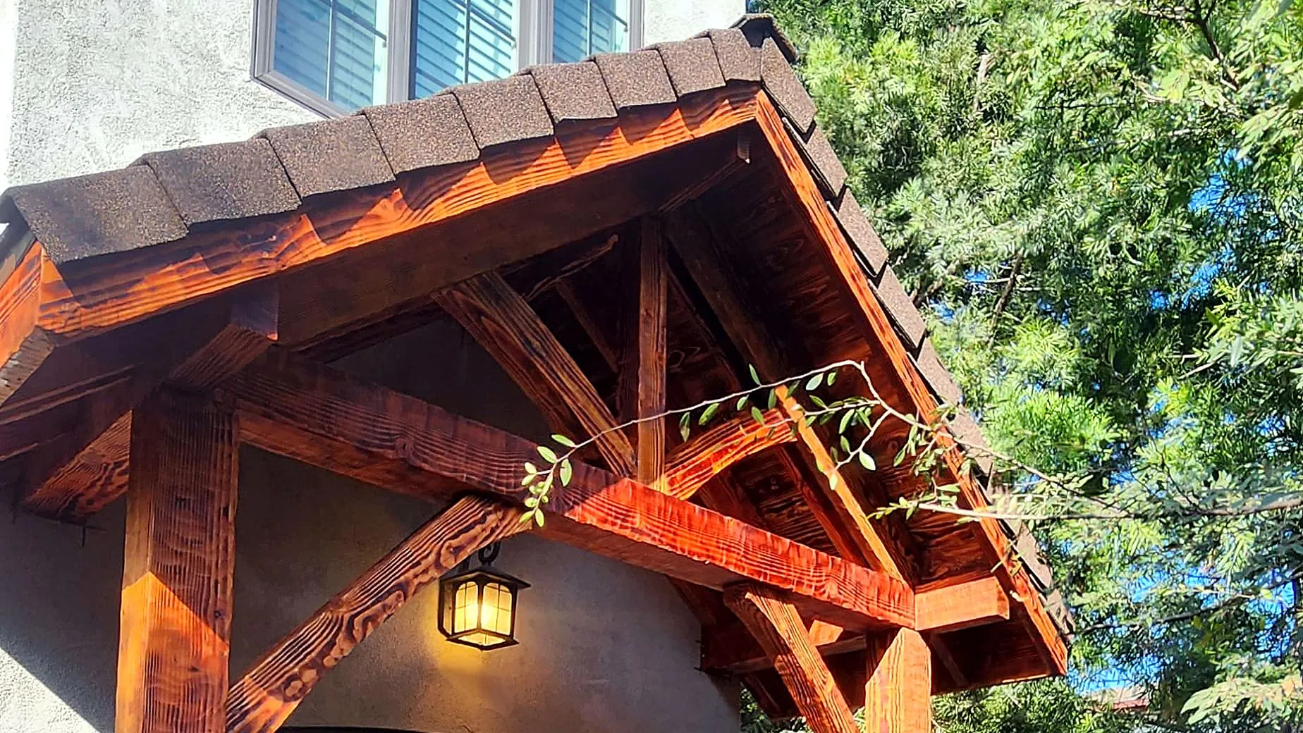 Stained timber portico with a pitched roof above a wooden double door