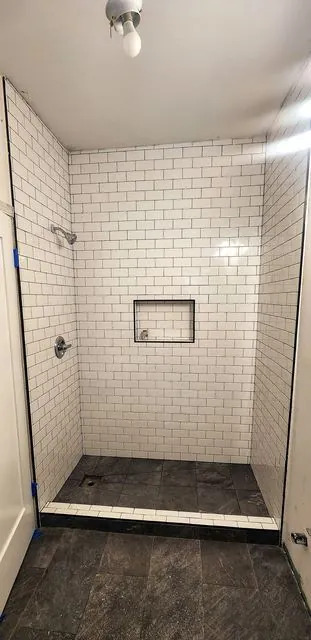 White subway tile shower with a niche